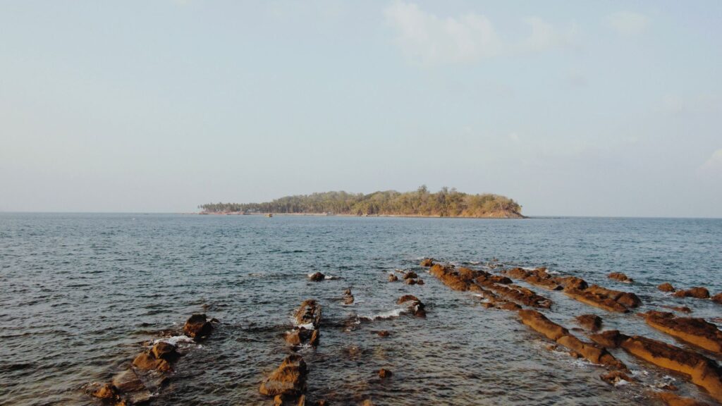 Tranquil ocean view with rocky shoreline and island in Port Blair, India.
