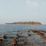 Tranquil ocean view with rocky shoreline and island in Port Blair, India.