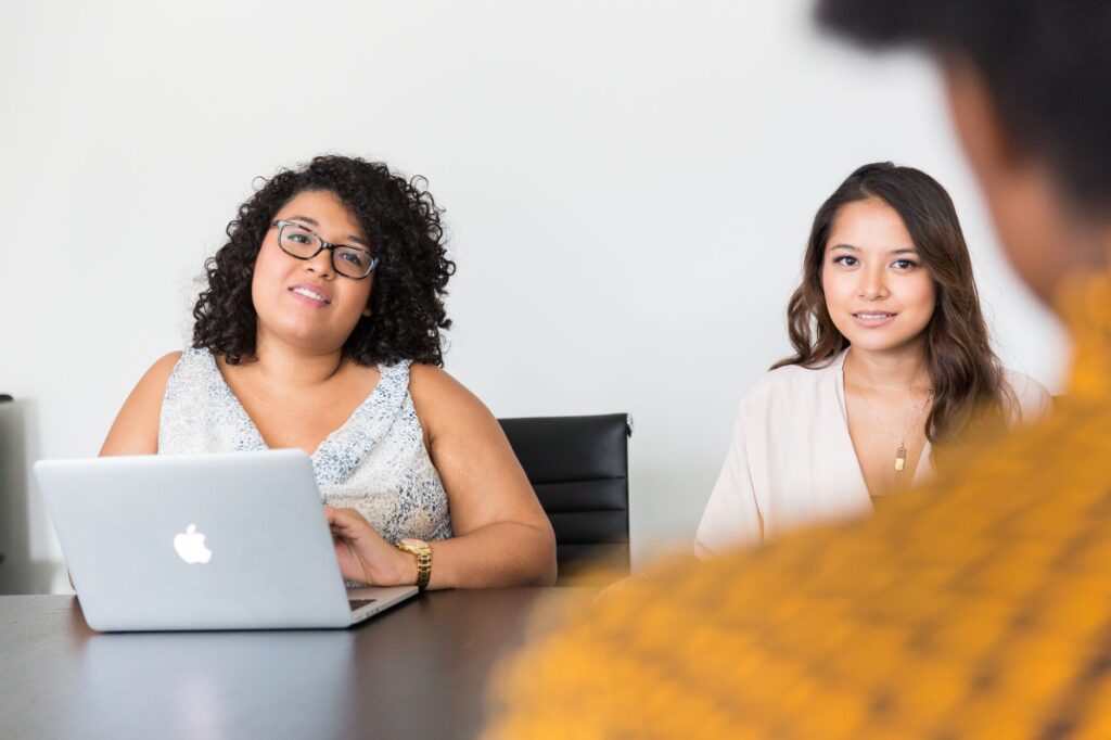 Diverse women engaged in a business meeting with laptop, showcasing teamwork and collaboration.