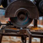 Close-up of a circular saw blade cutting metal, emitting sparks, in an industrial setting.