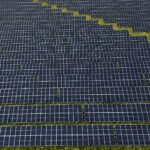 Aerial photograph capturing the geometric layout of a large solar panel farm. Sustainable energy focus.
