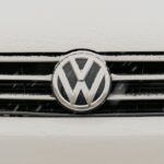 Closeup of a snow-dusted Volkswagen car grille shows the iconic VW logo.