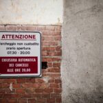Italian parking warning sign on brick wall. Indicates gate closure times.