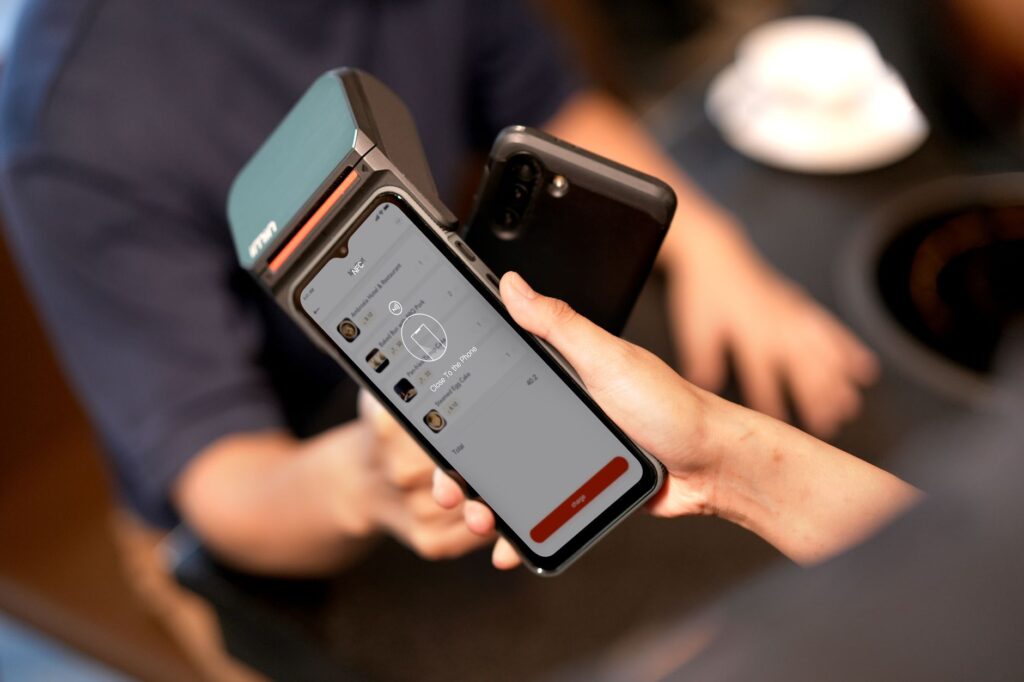 Close-up of a smartphone making a contactless payment at a modern payment terminal in a retail environment.
