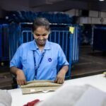 Female factory worker folding textiles on a production line, displaying focus and employment in the textile industry.