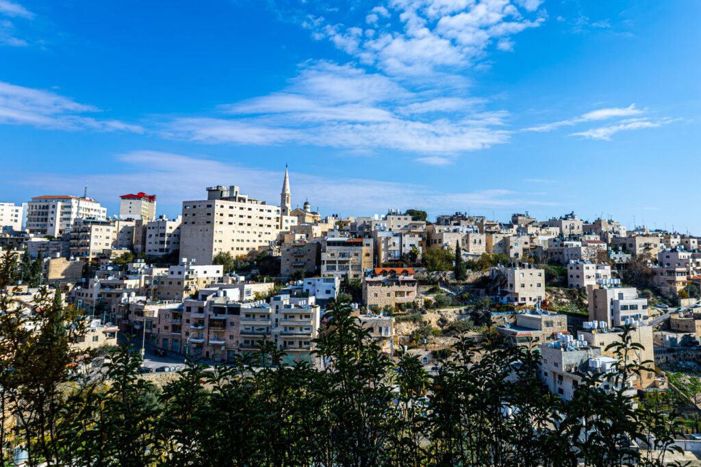 Explore the cityscape of Bethlehem with its distinctive architecture under a bright blue sky, showcasing traditional Middle Eastern urban life.