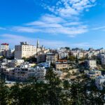 Explore the cityscape of Bethlehem with its distinctive architecture under a bright blue sky, showcasing traditional Middle Eastern urban life.
