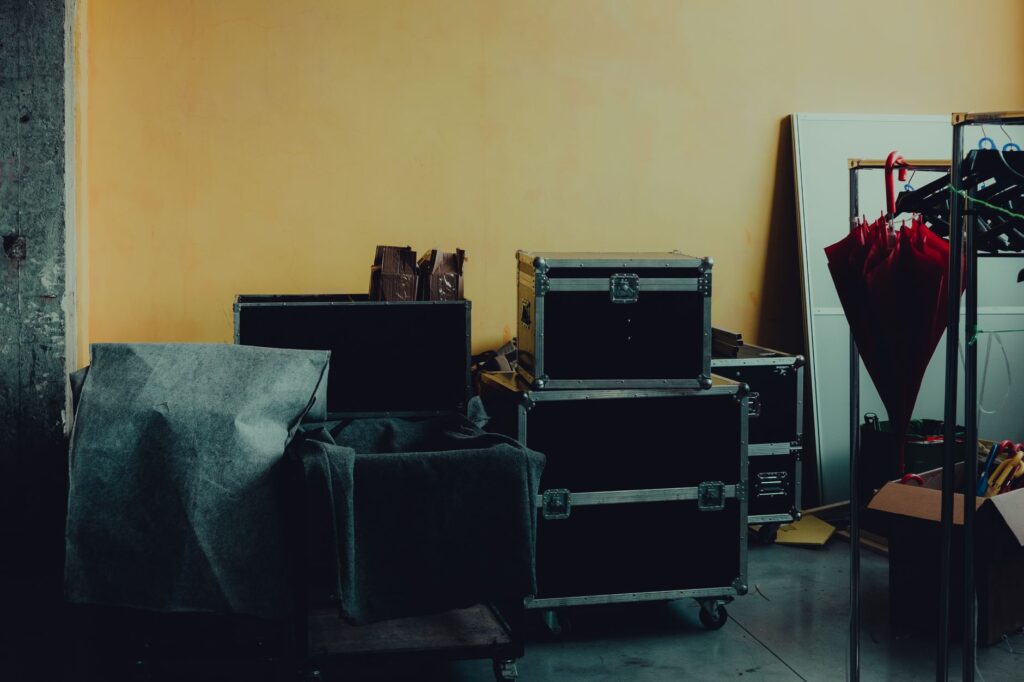 Many boxes and huge iron cases near umbrella placed in room with yellow walls
