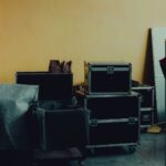 Many boxes and huge iron cases near umbrella placed in room with yellow walls