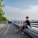 A person with a prosthetic leg relaxes by the riverfront in Ahmedabad, India, on a sunny day.