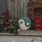 Rustic urban alley with yin-yang mosaic, Coca-Cola crates, and potted plants.