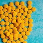 Bright yellow pills scattered on a vibrant blue background, resembling a healthcare theme.