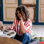 Casual young adult with dreadlocks working remotely on a laptop from home.