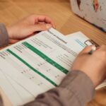 A person analyzing a return on investment report with a pen in hand on a desk.