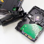 A collection of dismantled hard disk drives displayed on a white surface, showcasing internal components.