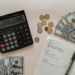 Flat lay of calculator, cash, coins, and handwritten notes for budget planning.