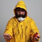 Portrait of a man in a yellow hazmat suit holding soil and a red apple, symbolizing contamination.