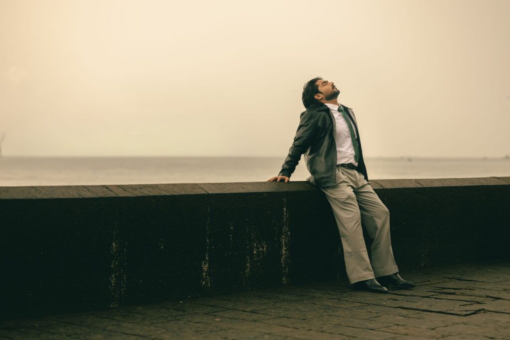 A businessman in a suit relaxes by the Mumbai waterfront, capturing a moment of calm.