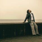 A businessman in a suit relaxes by the Mumbai waterfront, capturing a moment of calm.