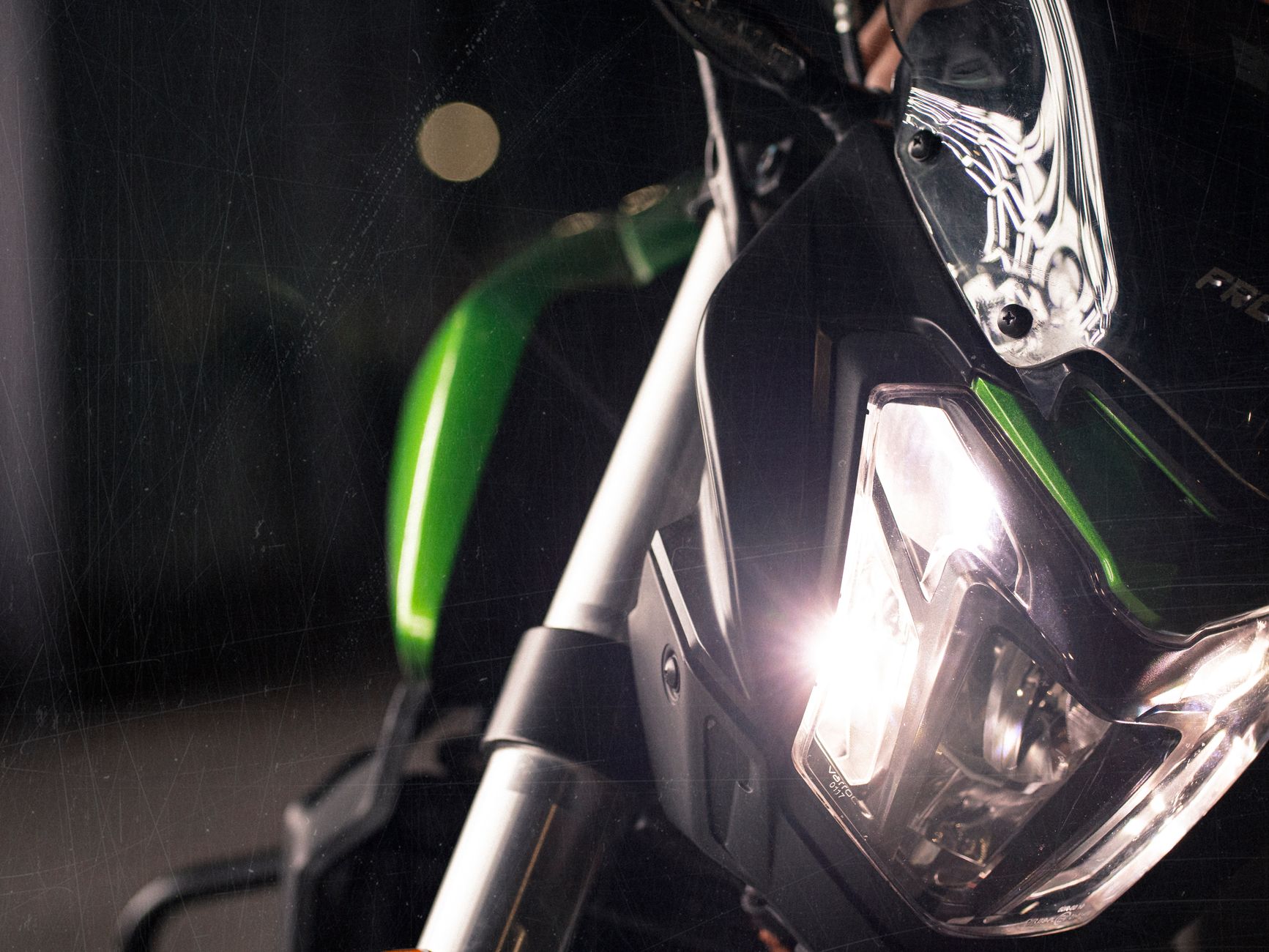Detailed view of a sports motorcycle's illuminated headlight at night. Captures modern design.
