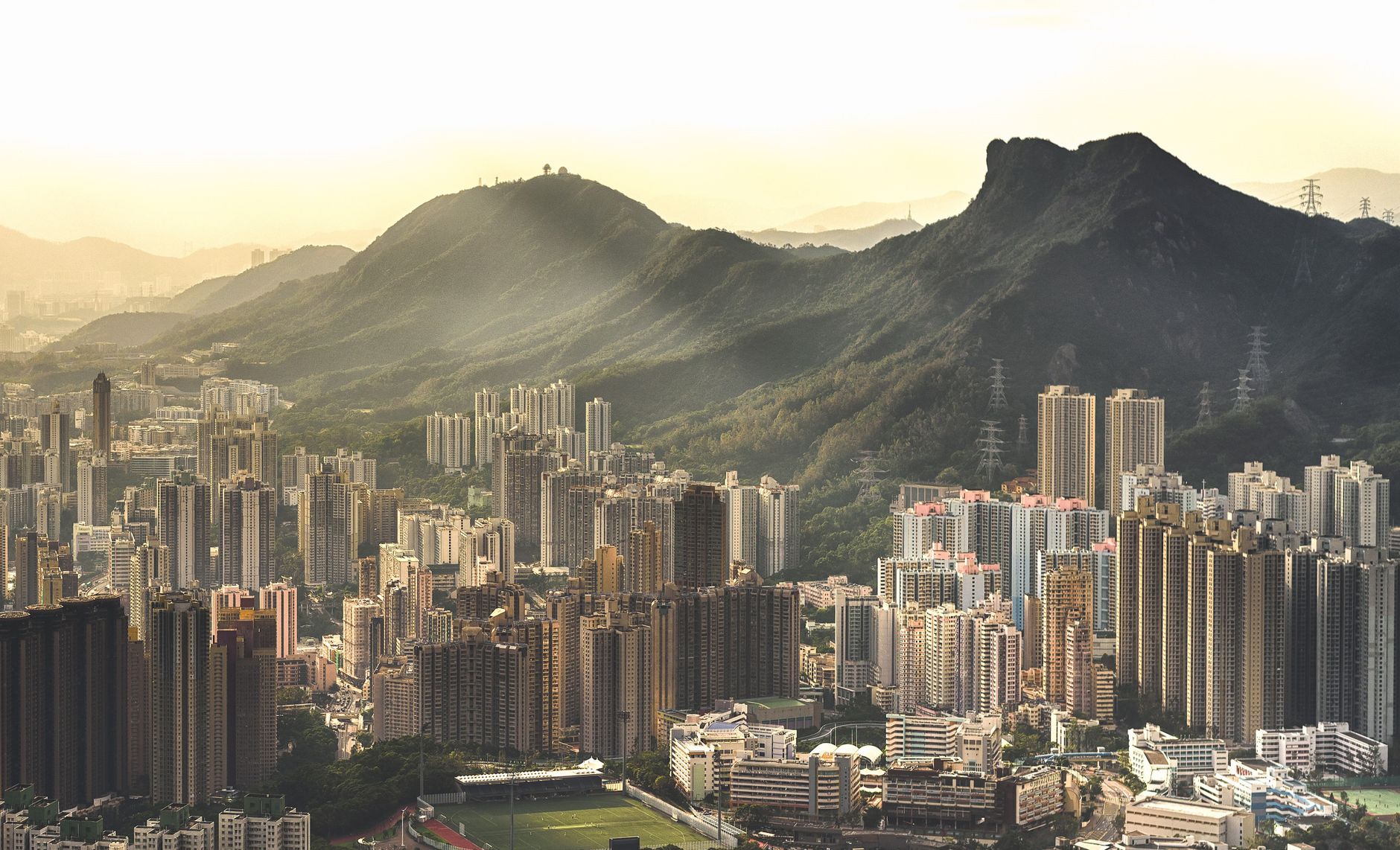 Aerial view of a sprawling city with mountain landscape at sunrise.