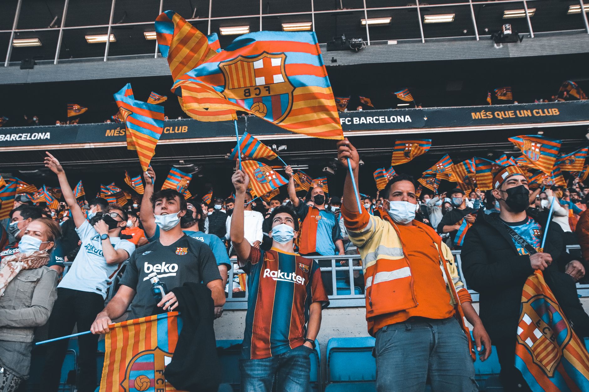 Fans enthusiastically wave FC Barcelona flags at a football match, showcasing team spirit and unity.