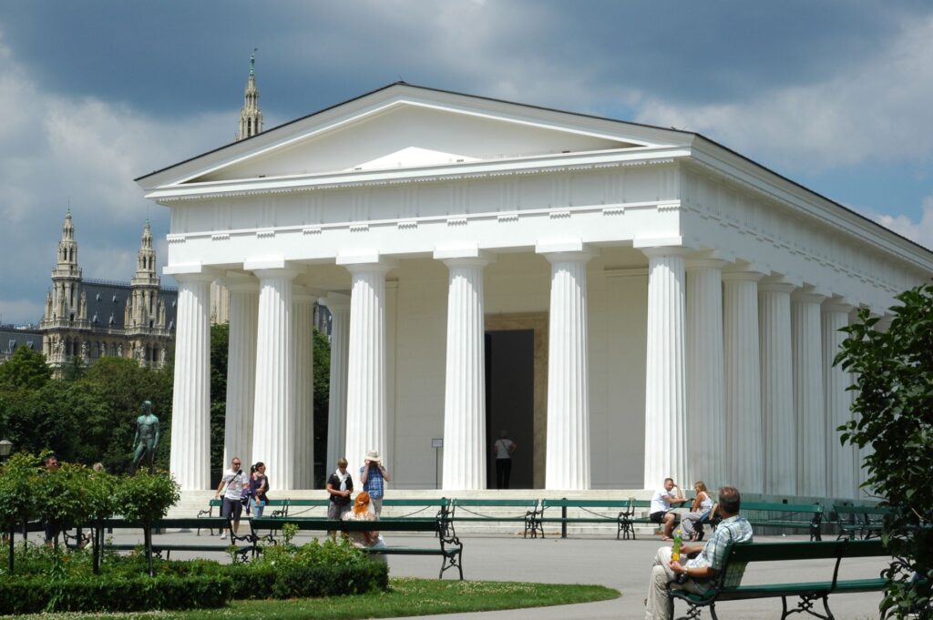 Captured in Burggarten, Vienna, this neoclassical temple stands against a vibrant city backdrop.