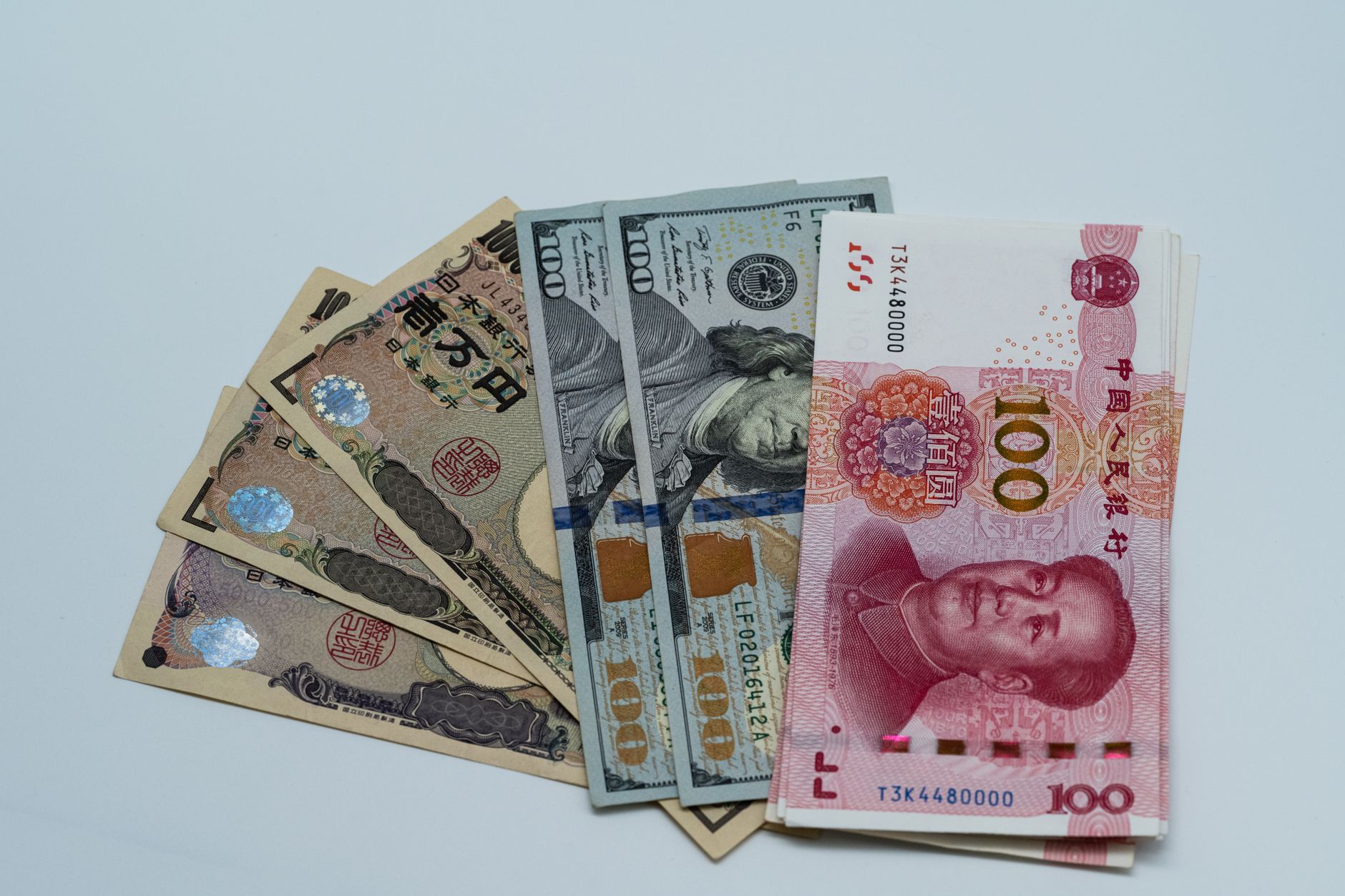 Various international currency notes including US dollars, yen, and yuan arranged on a surface.