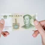 Close-up of hands holding a one Chinese Yuan note, showcasing currency details.