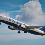 A Ryanair airplane ascends into the sky, showcasing its undercarriage and wing details.