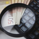 Euro bills under magnifying glass with calculator, symbolizing finance and analysis.