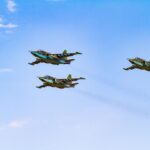 Sukhoi Su-25 aircrafts flying in perfect formation against a clear blue sky.