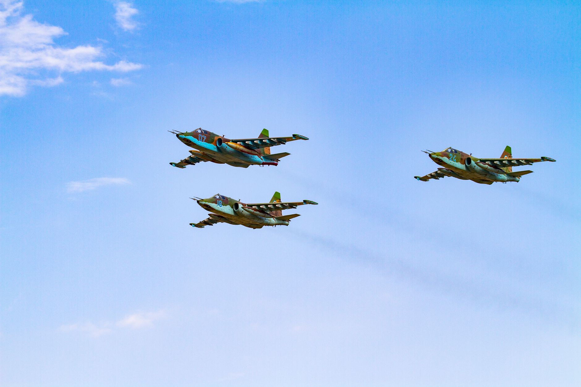 Sukhoi Su-25 aircrafts flying in perfect formation against a clear blue sky.