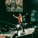 A vibrant luchador performs on stage in a lively wrestling event, thrilling a packed audience.