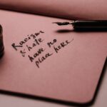 Ink pen and bottle on pink paper with motivational quote against racism and hate.