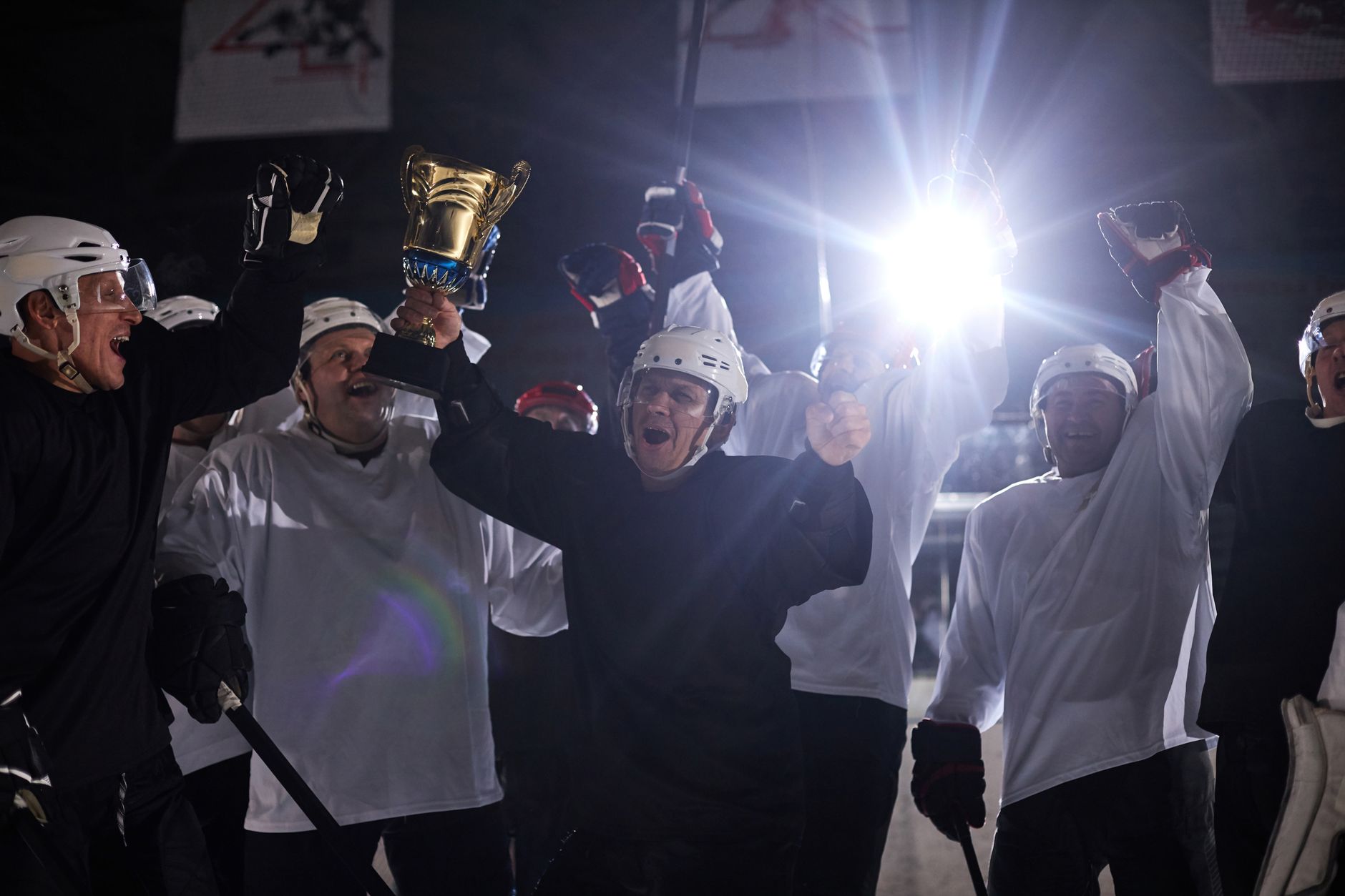 A joyful hockey team celebrates victory holding the trophy on the ice rink.