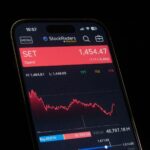 Close-up of a smartphone showing a stock market chart with financial data and analytics.