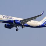 IndiGo commercial airline flying against a clear blue sky, signifying travel and aviation.