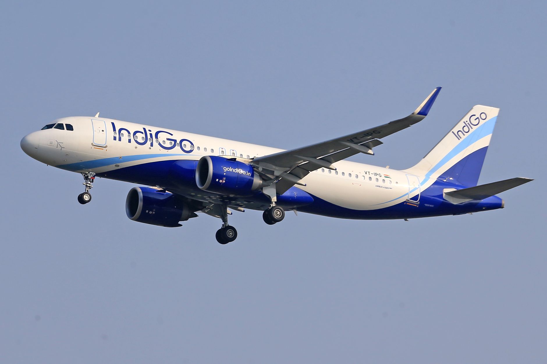 IndiGo commercial airline flying against a clear blue sky, signifying travel and aviation.