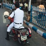 A Kolkata traffic police officer on a motorcycle manages traffic in a busy street in India.