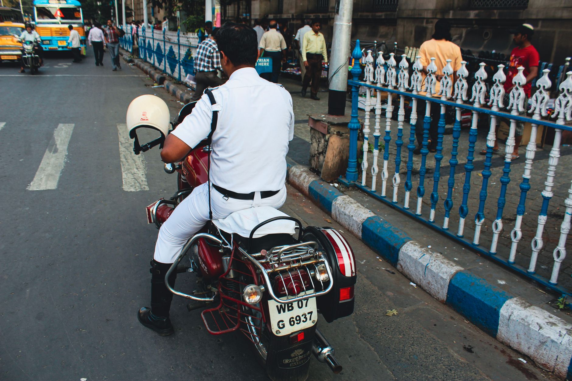 A Kolkata traffic police officer on a motorcycle manages traffic in a busy street in India.