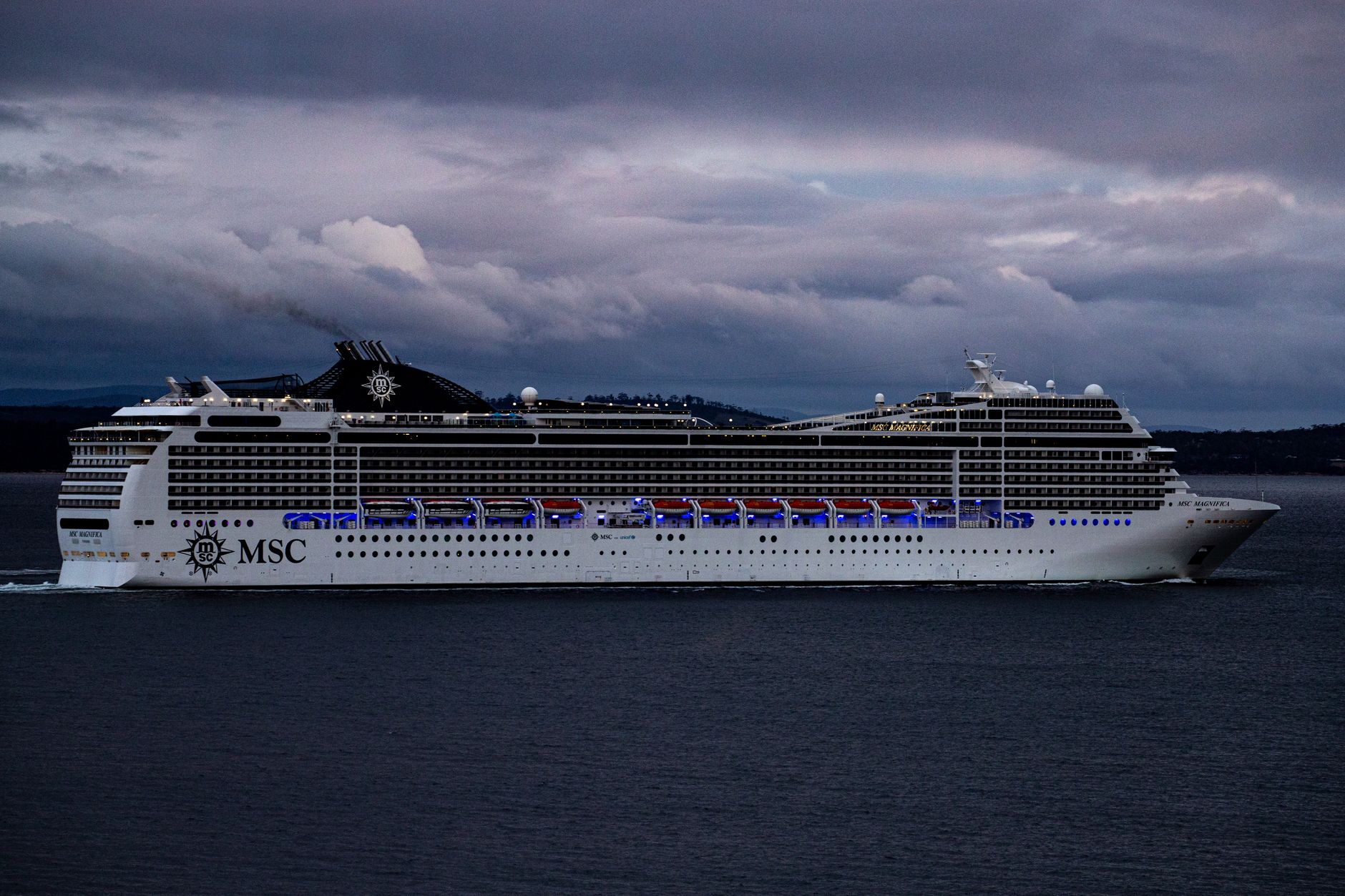 MSC cruise ship navigating waters near Hobart, Tasmania against a dramatic cloudy sky.