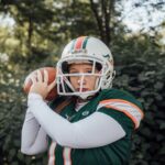 A female athlete in football gear practicing outdoors, showcasing strength and focus.