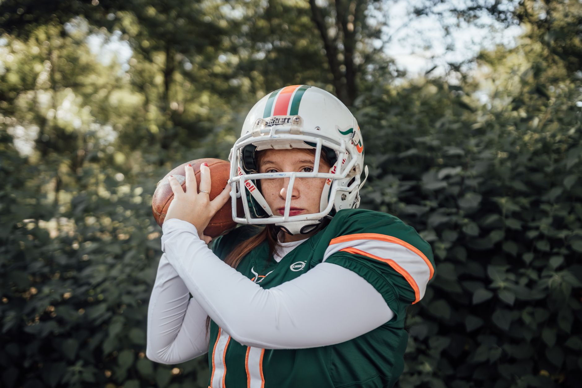 A female athlete in football gear practicing outdoors, showcasing strength and focus.
