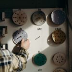 A person in a carpentry workshop selects sandpaper disks from a board in warm lighting.