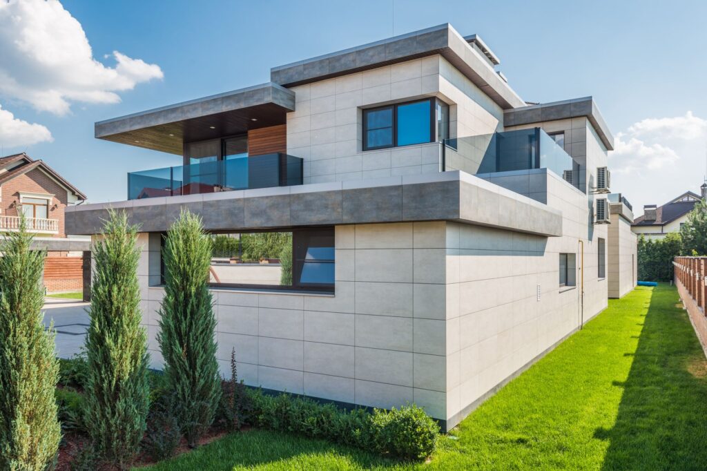 Contemporary two-story house with clean lines surrounded by green grass and blue sky.