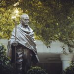 Bronze statue of Mahatma Gandhi surrounded by greenery in a serene garden in Delhi, India.