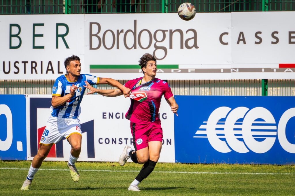 Two soccer players compete intensely for the ball during a vibrant outdoor match.