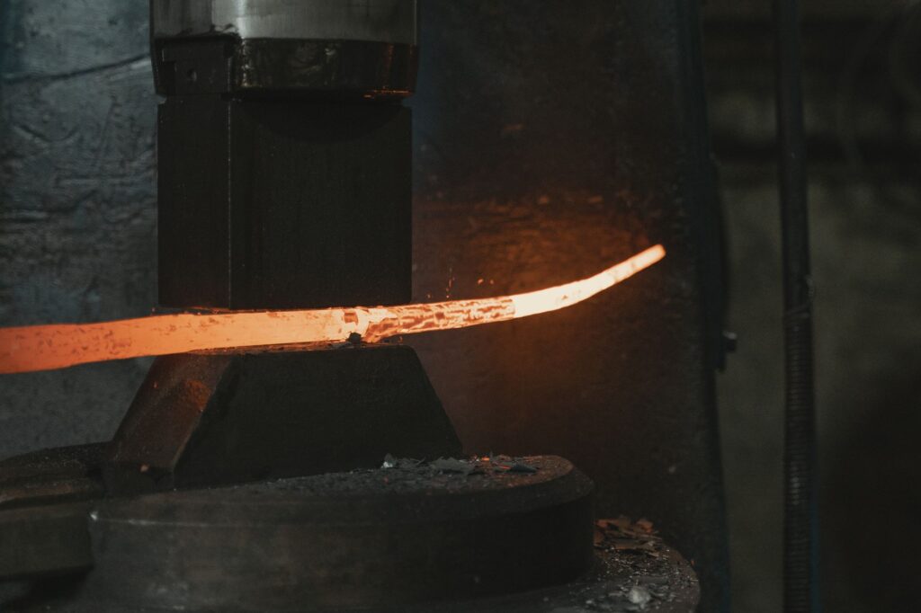 Close-up of hot iron being shaped in a forge, highlighting intense heat and craftsmanship.