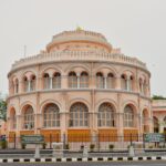 A beautiful pink circular building with arched windows and ornate architecture in a city setting.